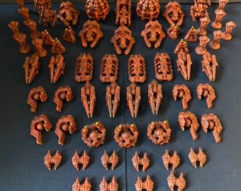 May include: A collection of 45 miniature spaceships in various shapes and sizes, all painted in a rusty brown color with yellow accents. The spaceships are arranged in rows on a dark surface.
