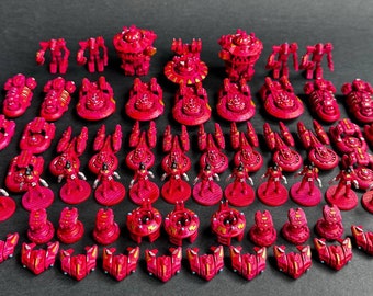 May include: A collection of red and gold painted miniature spaceships, fighters, and ground units. The miniatures are arranged in rows on a dark surface.