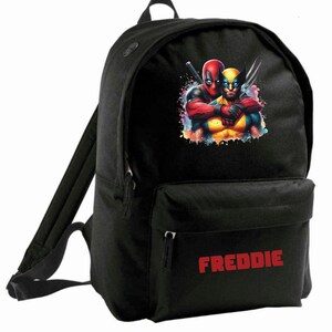 May include: Black backpack featuring a colourful graphic of Deadpool and Wolverine. The backpack has a front pocket with the name "FREDDIE" printed in red.