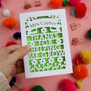 May include: White card with a green cutout design. The card says "Mrs. Carter" and "Thanks for helping me grow".