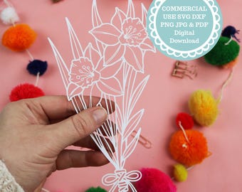 May include: White paper cut-out of a bouquet of daffodils with a bow at the bottom. The text "COMMERCIAL USE SVG DXF PNG JPG & PDF Digital Download" is in a circle at the top of the image.