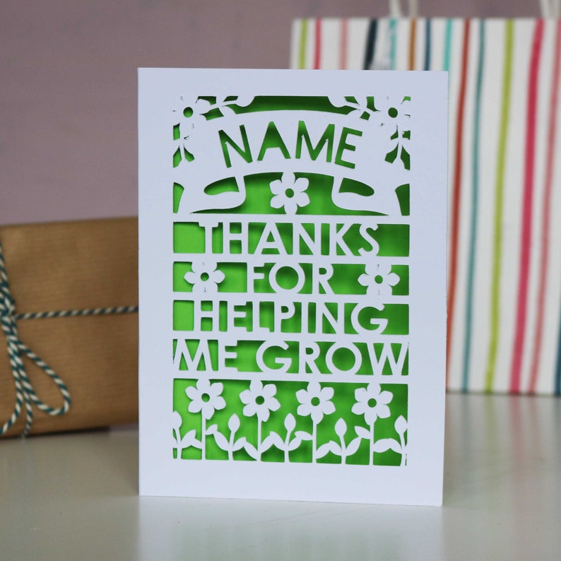 May include: White card with a green background and a cut-out design. The card says "NAME THANKS FOR HELPING ME GROW".