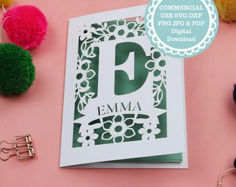May include: White card with a floral cut-out design, featuring the letter "E" and the name "EMMA" on a green background. The card is surrounded by decorative elements and the text "COMMERCIAL USE SVG DXF PNG JPG & PDF Digital Download".