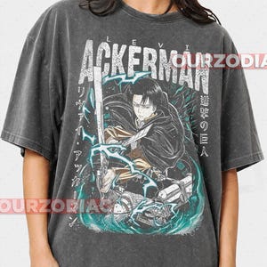 May include: Dark grey t-shirt with a graphic of a character with a sword, the text "LEVI ACKERMAN" and Japanese text. The design includes blue and white lightning effects. The shirt has a vintage, worn appearance.