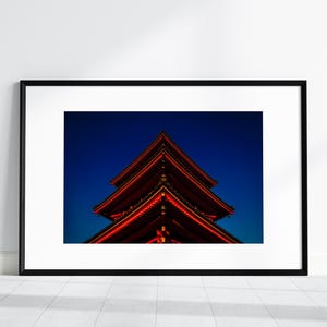 May include: A red pagoda with a dark blue sky in the background. The pagoda is lit up with red lights, creating a striking contrast against the night sky.