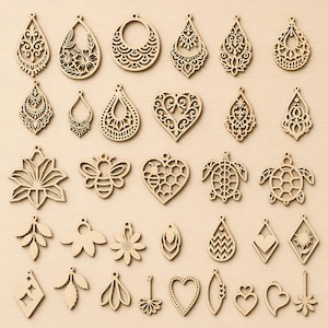 May include: A collection of thirty-four light brown wooden laser-cut pendants in various shapes including teardrops, hearts, flowers, a bee, and turtles. Each piece features intricate cut-out patterns and a small hole at the top for hanging.