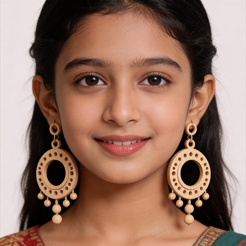 May include: A pair of light-colored wooden dangle earrings featuring a large circular frame with a series of small cut-out holes along the inner edge and five small spherical beads hanging from the bottom of each circular component.