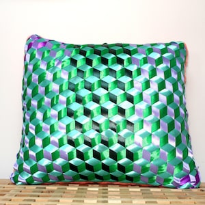 Puede incluir: Una almohada cuadrada con un patrón geométrico hecho de cinta de satén verde, morado y negro.