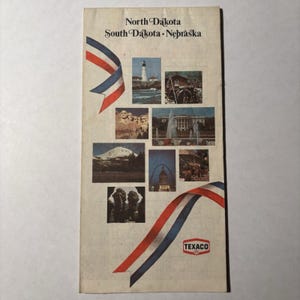 May include: A vintage Texaco travel map brochure titled North Dakota, South Dakota, Nebraska. The cover features a collage of American landmarks, including Mount Rushmore and the Gateway Arch, accented by red, white, and blue ribbon graphics.