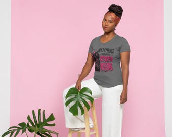 Op de afbeelding: Een donkergrijs T-shirt met korte mouwen voorzien van een afbeelding van een zwarte kat met roze accenten en de tekst "MY PATIENCE HAS BEEN REPORTED MISSING" in zwarte en roze letters. Het shirt heeft een ronde hals en een getailleerde pasvorm.