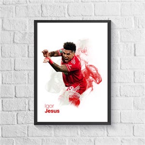 May include: Framed print of a soccer player in a red kit, celebrating with arms raised. Red and white smoke-like effects surround the player. The name "Igor Jesus" is printed in red at the bottom of the image, set against a white background.