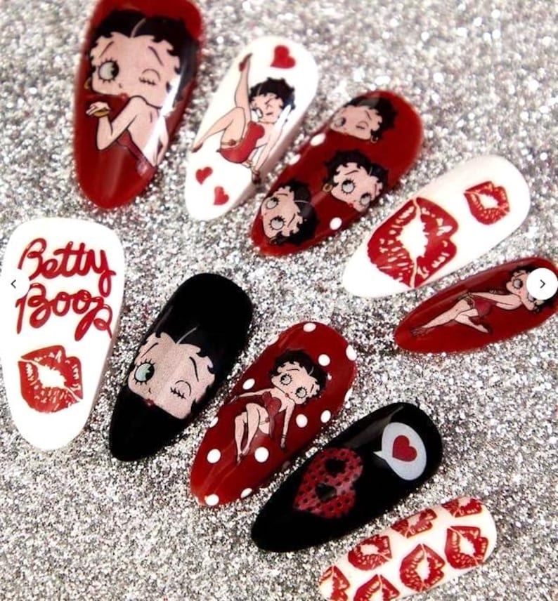 May include: A selection of artificial nails decorated with Betty Boop designs. The nails display Betty Boop in red, black, and white, with polka dots, hearts, and the text "Betty Boop".