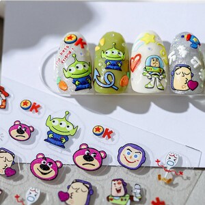 May include: A sheet of clear nail stickers with Toy Story characters. The stickers feature Woody, Buzz Lightyear, and Alien. The stickers are perfect for adding a fun and whimsical touch to your nails.