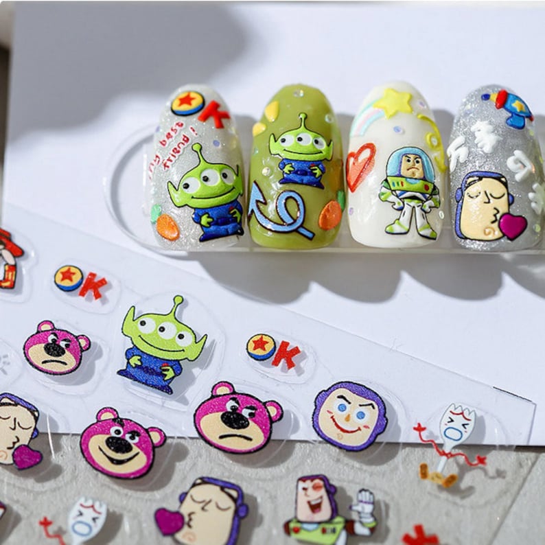 May include: A sheet of clear nail stickers with Toy Story characters. The stickers feature Woody, Buzz Lightyear, and Alien. The stickers are perfect for adding a fun and whimsical touch to your nails.