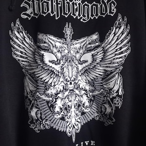 May include: Black hoodie with a white graphic print of a wolf with wings and a sword. The text "Wolfbrigade" is at the top of the graphic and "COMALIVE" is at the bottom.