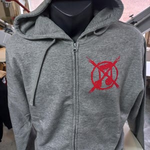 May include: A gray zippered hoodie with a red graphic of a circle with a crossed-out hourglass inside. The graphic is on the front of the hoodie.