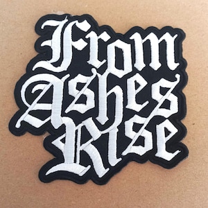 May include: Black and white embroidered patch with the words "From Ashes Rise" in a gothic font.