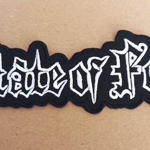 Puede incluir: Parche bordado en blanco y negro con el texto "Siege of Power" en una fuente gótica.