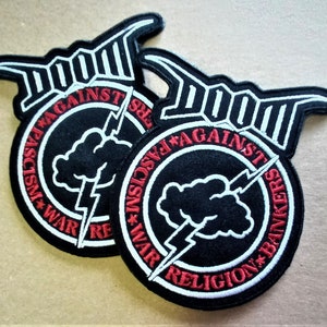 May include: Two black and white embroidered patches with the word "DOOM" in white lettering and the words "AGAINST WAR * FASCISM * RELIGION * BANKERS" in red lettering around a black cloud with a white lightning bolt.