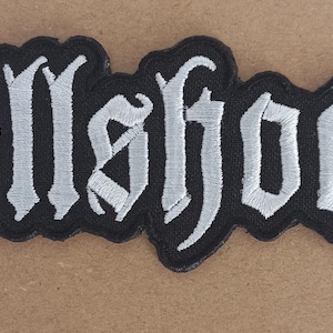 May include: A black and white embroidered patch with the word "hellshock" in a gothic font.