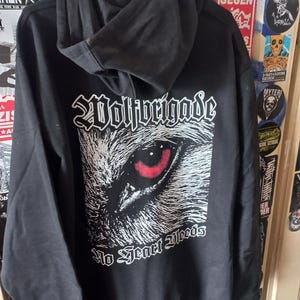 Può includere: Felpa con cappuccio nera con una grafica di un occhio di lupo e il testo "Wolfbrigade No Fear Bleeds".