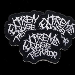 Peut inclure: Trois patchs brodés noirs avec des points blancs. Chaque patch porte l'inscription "Extreme Noise Terror".