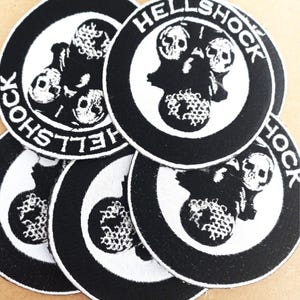 May include: A set of five black and white embroidered patches with the text "HELLSHOCK" in a circle around a skull graphic.