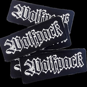 Pode incluir: Quatro patches de tecido preto com texto bordado branco que diz "Wolfpack".
