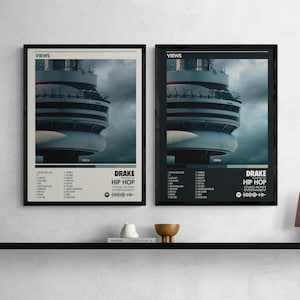 May include: Two framed posters featuring the Drake album "Views." The posters display a photo of a tower against a cloudy sky. The text includes "VIEWS," song titles, and "DRAKE HIP HOP." One poster has a cream background, the other is black.