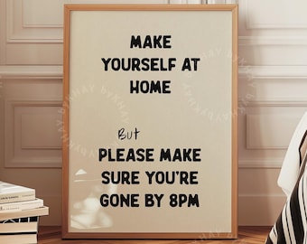May include: A framed print with the text "Make yourself at home, but please make sure you're gone by 8pm". The print is hanging on a wall in a room with a bed and a wooden floor.
