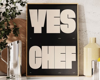 May include: A black framed poster with the text "YES CHEF" in white letters on a beige background. The poster is sitting on a white countertop with a vase of greenery, a pitcher, a glass, and a bowl of lemons.