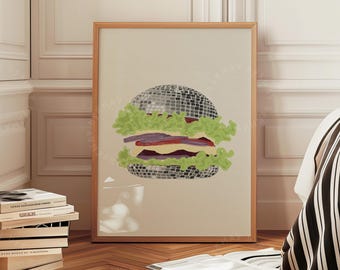 May include: A framed print featuring a whimsical burger design. The burger's top bun is a disco ball, with lettuce, tomato, and a patty. The artwork is displayed in a light-colored wooden frame, adding a touch of fun to any space.