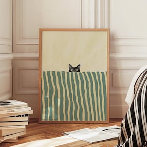 May include: A framed art print with a minimalist design. The artwork shows a black cat peeking over a green and white striped barrier against a cream background. The print is in a wooden frame, suitable for home decor.