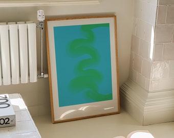 May include: A framed abstract print with a green and blue design. The print is hanging on a white wall next to a white radiator. A book and a paintbrush are on the floor.
