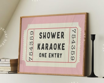 Puede incluir: Una impresión enmarcada en rosa de un boleto vintage con el texto "Shower Karaoke One Entry" en negro. El número del boleto es 754359. Dos candelabros negros están sobre una superficie blanca debajo de la impresión.