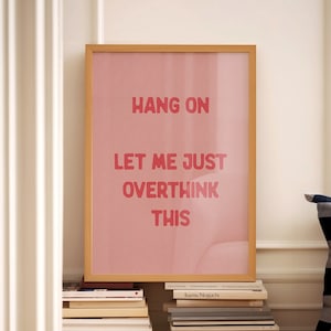 May include: A framed print with a pink background and the text "HANG ON LET ME JUST OVERTHINK THIS" in red.