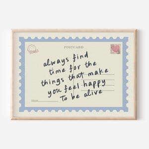 May include: A framed postcard print with a light beige background and a blue border. The text reads "always find time for the things that make you feel happy to be alive" in black handwritten font.