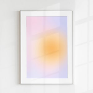 May include: A framed abstract print with a gradient of pink, purple, and yellow colors. The print has a blurred, soft focus effect.