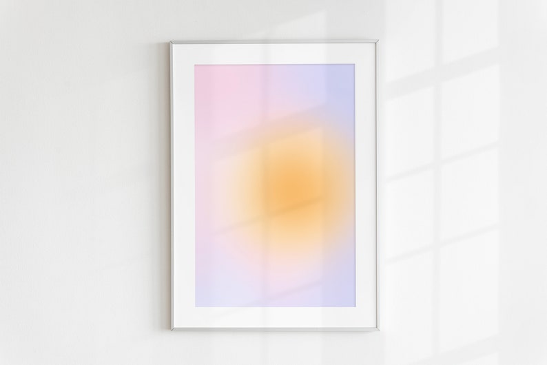 May include: A framed abstract print with a gradient of pink, purple, and yellow colors. The print has a blurred, soft focus effect.