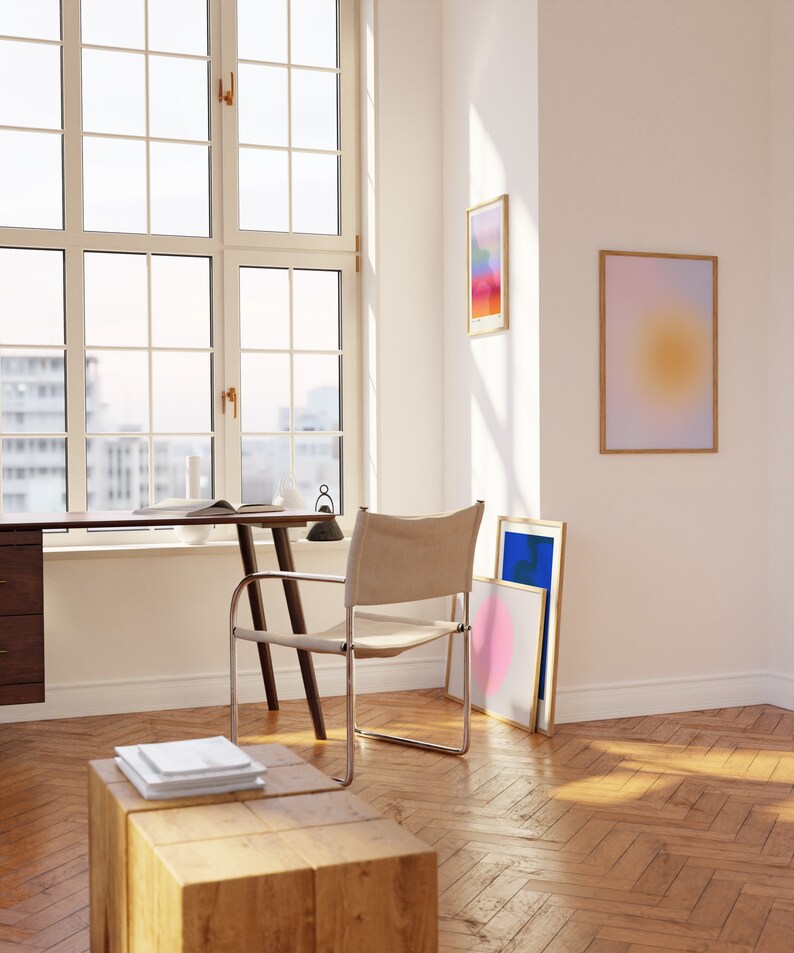 May include: A light wood desk with a white chair and a lamp. There are three framed abstract art prints on the wall behind the desk. The room has hardwood floors.