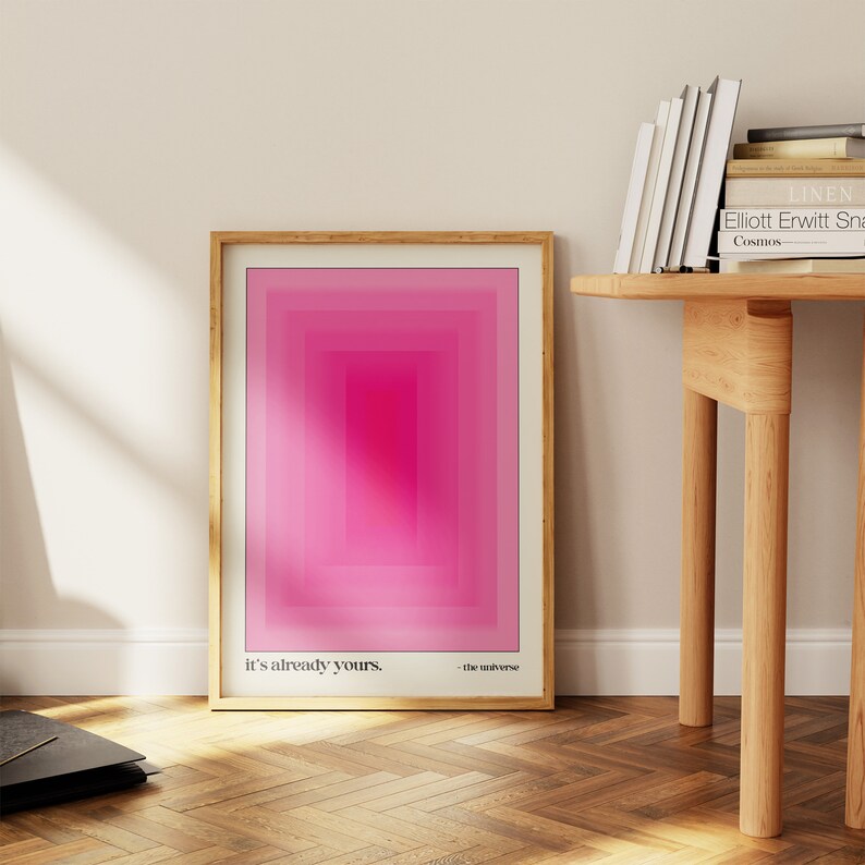 May include: A framed print with a pink and white geometric design. The print has the text "it's already yours." and "the universe" at the bottom.