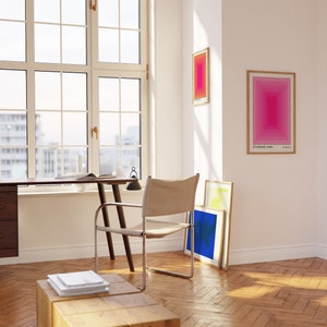 May include: A wooden desk with a chair and a stack of papers on a wooden stool. The desk is next to a large window with a view of a city. There are three framed prints on the wall, one with the text "It's already yours."