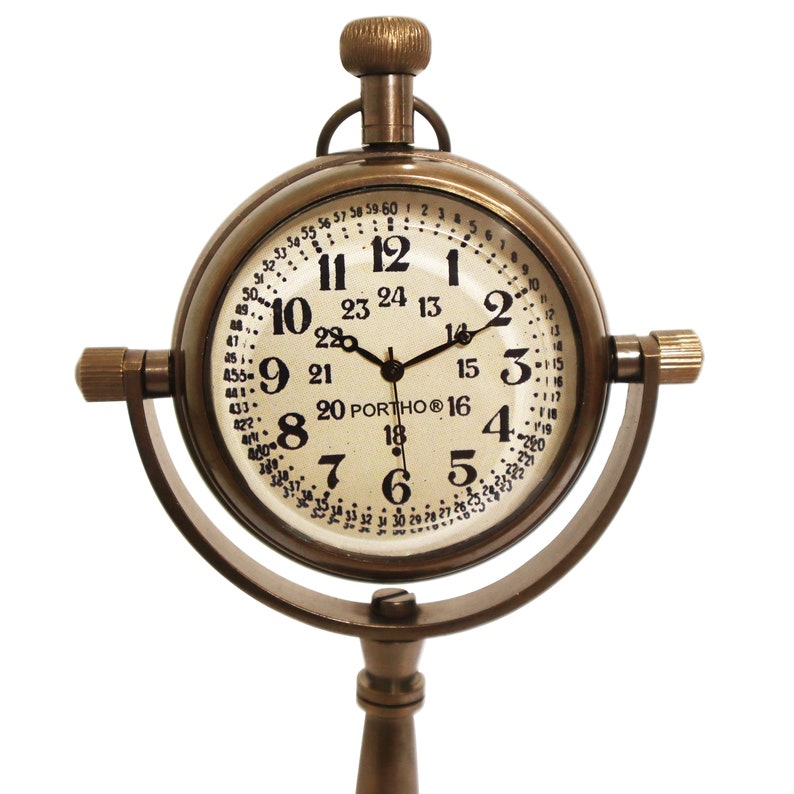 K&ouml;nnte beinhalten: Eine antike Messing-Uhr mit einem runden Zifferblatt und schwarzen Zeigern. Die Uhr hat einen Standfu&szlig; mit einem runden Sockel und einem langen, d&uuml;nnen Stiel. Das Zifferblatt der Uhr hat r&ouml;mische Ziffern und eine 24-Stunden-Zeitskala.