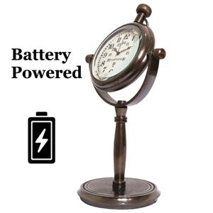 K&ouml;nnte beinhalten: Eine antike Uhr mit einem runden Zifferblatt und einem Messingst&auml;nder. Die Uhr ist batteriebetrieben und hat eine Lupe &uuml;ber dem Zifferblatt mit den Worten "20 Portmore 16" auf dem Zifferblatt.