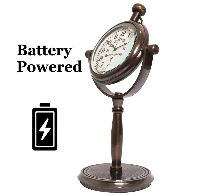 K&ouml;nnte beinhalten: Eine antike Uhr mit einem runden Zifferblatt und einem Messingst&auml;nder. Die Uhr ist batteriebetrieben und hat eine Lupe &uuml;ber dem Zifferblatt mit den Worten "20 Portmore 16" auf dem Zifferblatt.