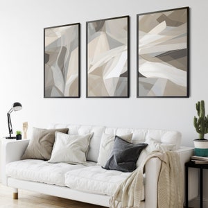 Puede incluir: Tres impresiones de arte abstracto en marcos negros con un esquema de color beige, gris y blanco. Las impresiones presentan formas geométricas y líneas.