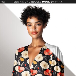 May include: A woman with short, curly black hair is wearing a black silk kimono blouse with a floral print. The print features red, white, and yellow flowers on a black background.