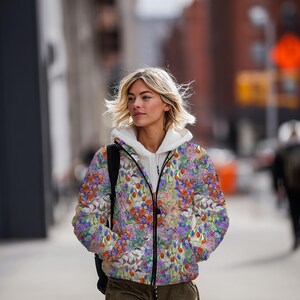 May include: A floral print jacket with a white hooded sweatshirt underneath. The jacket features a vibrant pattern of red, purple, and blue flowers on a white background. The jacket is zipped up and worn outdoors.