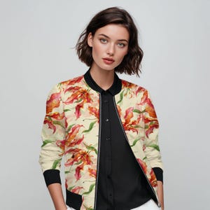 May include: A cream-coloured bomber jacket featuring a bold floral design in red, orange, and yellow hues. The jacket has a black collar, cuffs, and hem. It is worn over a black collared shirt.