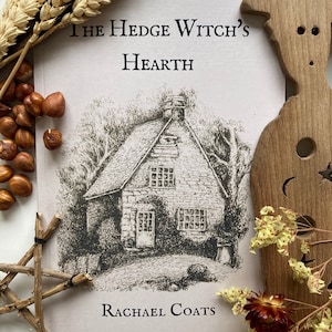 May include: A book cover with a drawing of a house and the title "The Hedge Witch's Hearth" by Rachael Coats.